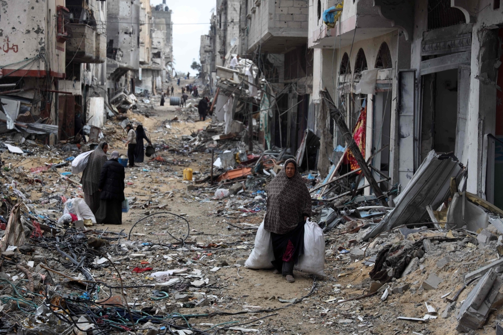 Palestinians carry some of their belongings after returning briefly to Khan Yunis in the southern Gaza Strip to check on what remains of their homes on March 7, 2024. Photo by AFP