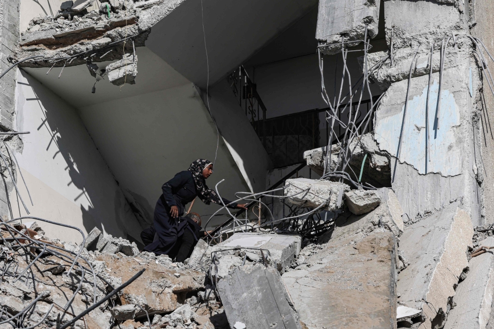 A Palestinian woman searches amid the rubble of a residential building hit in an overnight Israeli air strike in Rafah in the southern Gaza Strip on March 9, 2023. (Photo by Said Khatib / AFP)
