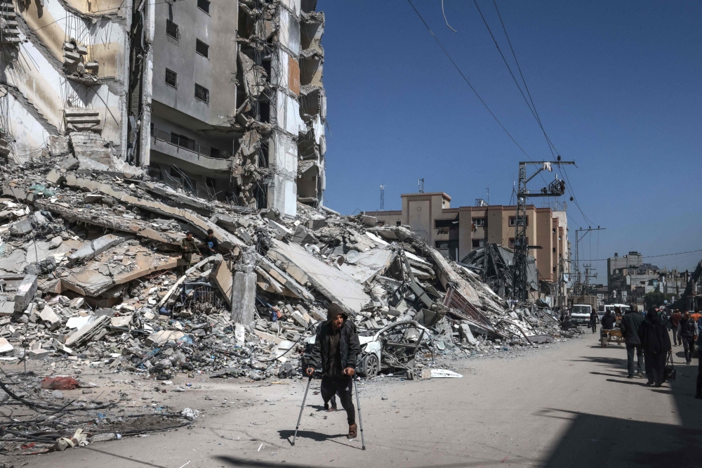 Palestinians walk past the rubble of a destroyed building due to Israeli bombardment on the second day of Ramadan in Rafah. Photo by MOHAMMED ABED / AFP