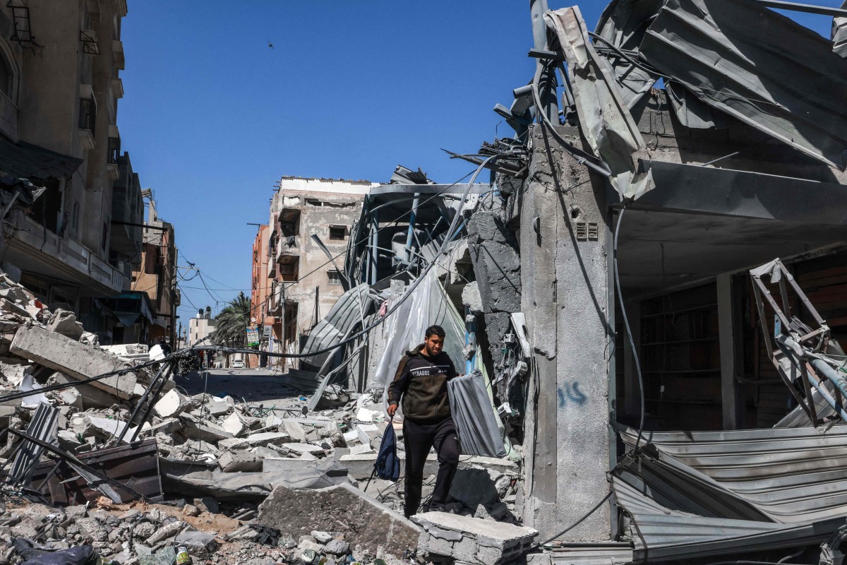 A Palestinian man walks through the rubble of a destroyed building due to Israeli bombardment in Rafah in the southern Gaza Strip on the second day of the Muslim holy fasting month of Ramadan on March 12, 2024. (Photo by MOHAMMED ABED / AFP)
