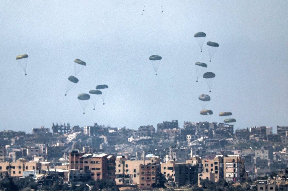 This picture taken from Israel's southern border with the Gaza Strip shows humanitarian aid being airdropped over the Palestinian territory on March 13, 2024. (Photo by Jack Guez / AFP)