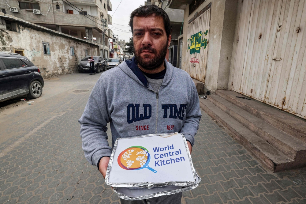 A man carries food aid packages provided by the non-profit non-governmental organisation World Central Kitchen, in Rafah in the southern Gaza Strip on March 17, 2024, amid the ongoing conflict between Israel and the militant group Hamas. (Photo by MOHAMMED ABED / AFP)
