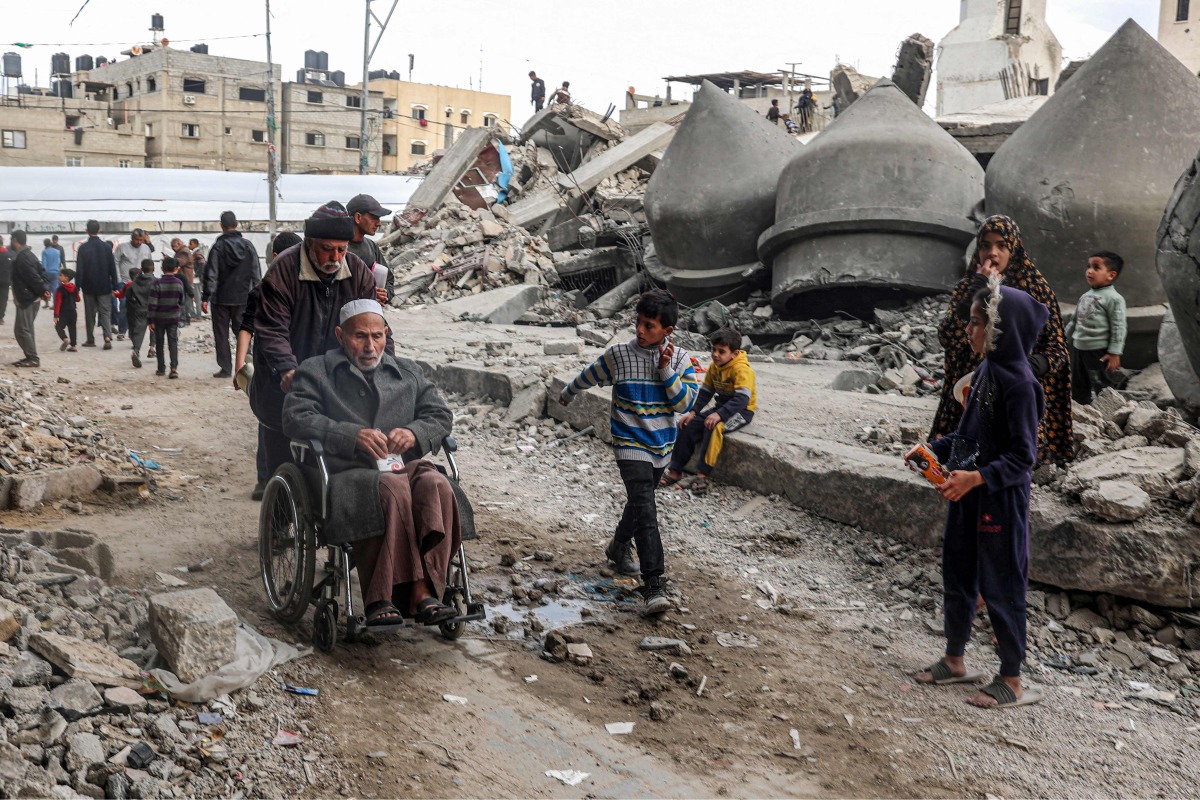 People walk past the rubble of Al-Faruq Mosque, that was destroyed during Israeli bombardment, in Rafah on the southern gaza Strip on March 17, 2024. (Photo by SAID KHATIB / AFP)