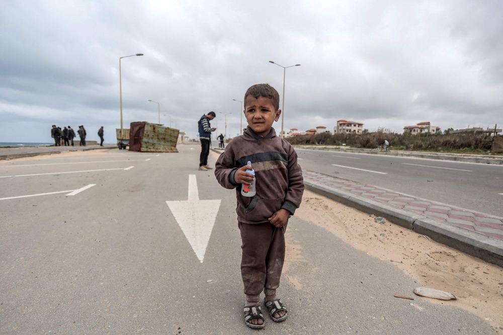 A child reacts as he walks along the coastal highway with other displaced Palestinians fleeing from the area in the vicinity of Gaza City's al-Shifa hospital, upon arrival at the Nuseirat refugee camp in the central Gaza Strip on March 18, 2024. (Photo by AFP)
