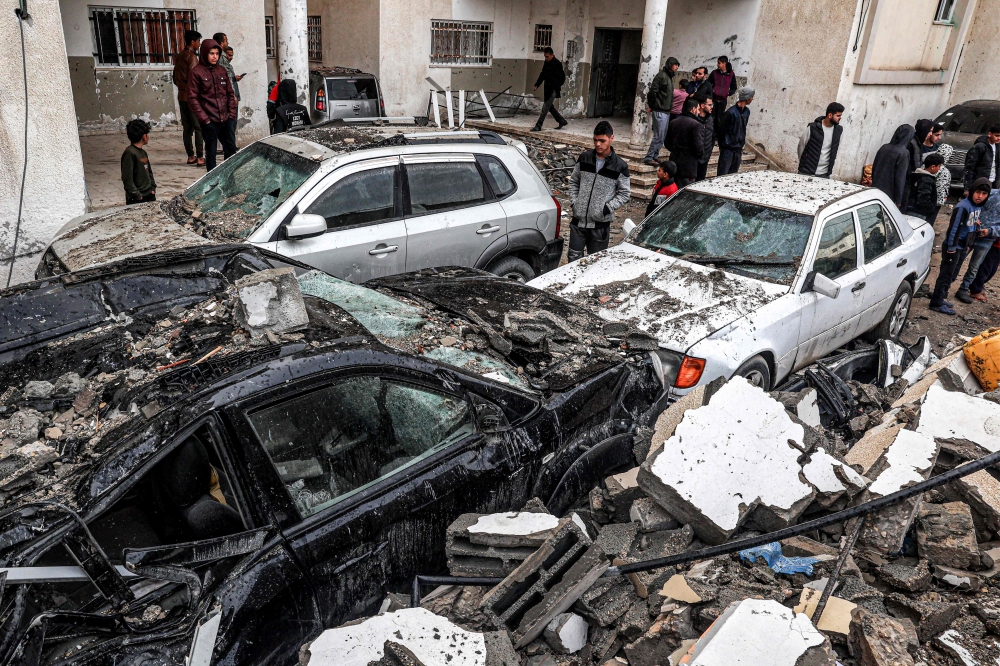 People inspect destroyed vehicles following overnight Israeli bombardment at the Rafah refugee camp in the southern Gaza Strip on March 19, 2024. (Photo by SAID KHATIB / AFP)
