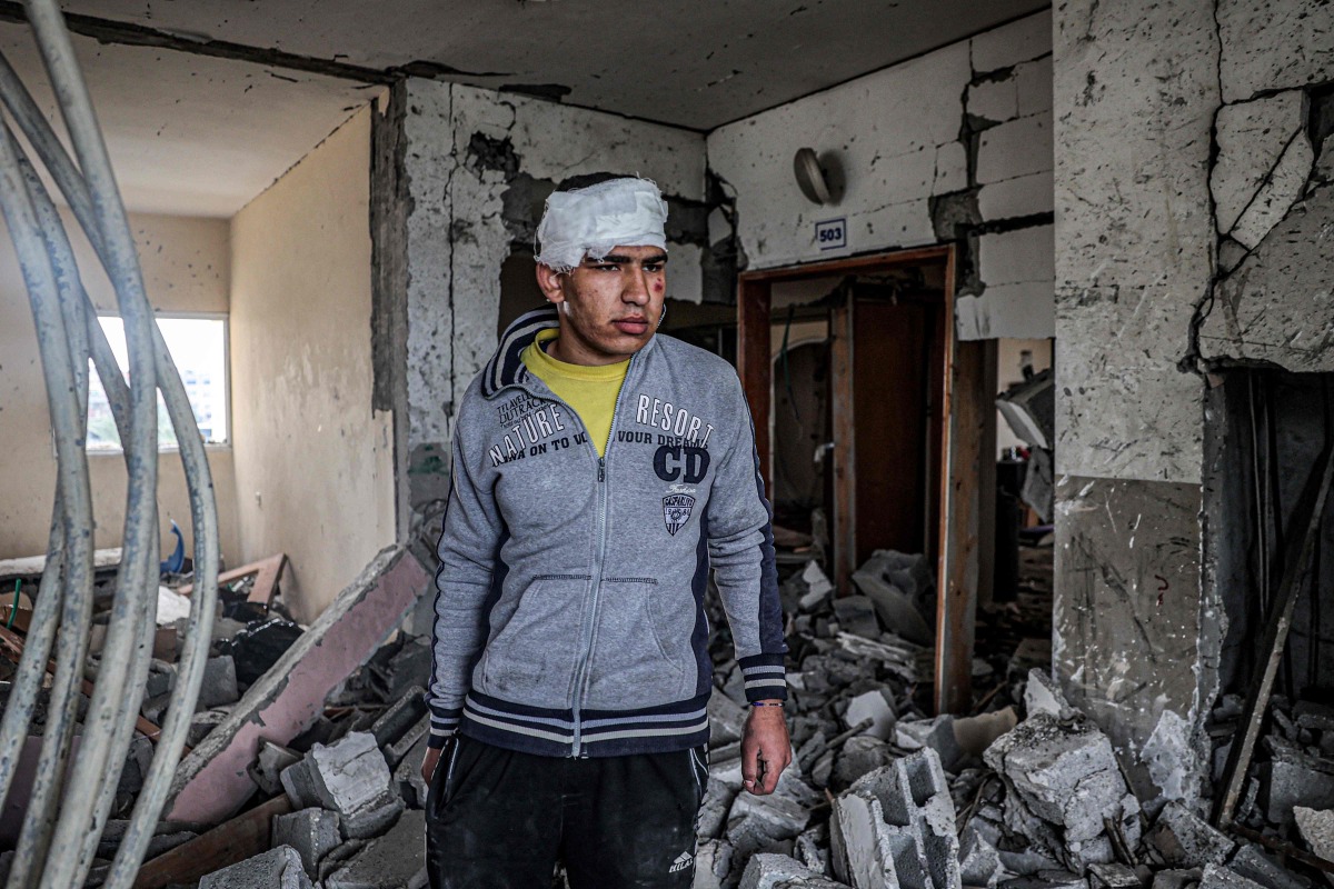 An injured boy inspects the rubble and debris of a building that was hit by overnight Israeli bombardment in Rafah in the southern gaza Strip on March 19, 2024. (Photo by SAID KHATIB / AFP)
