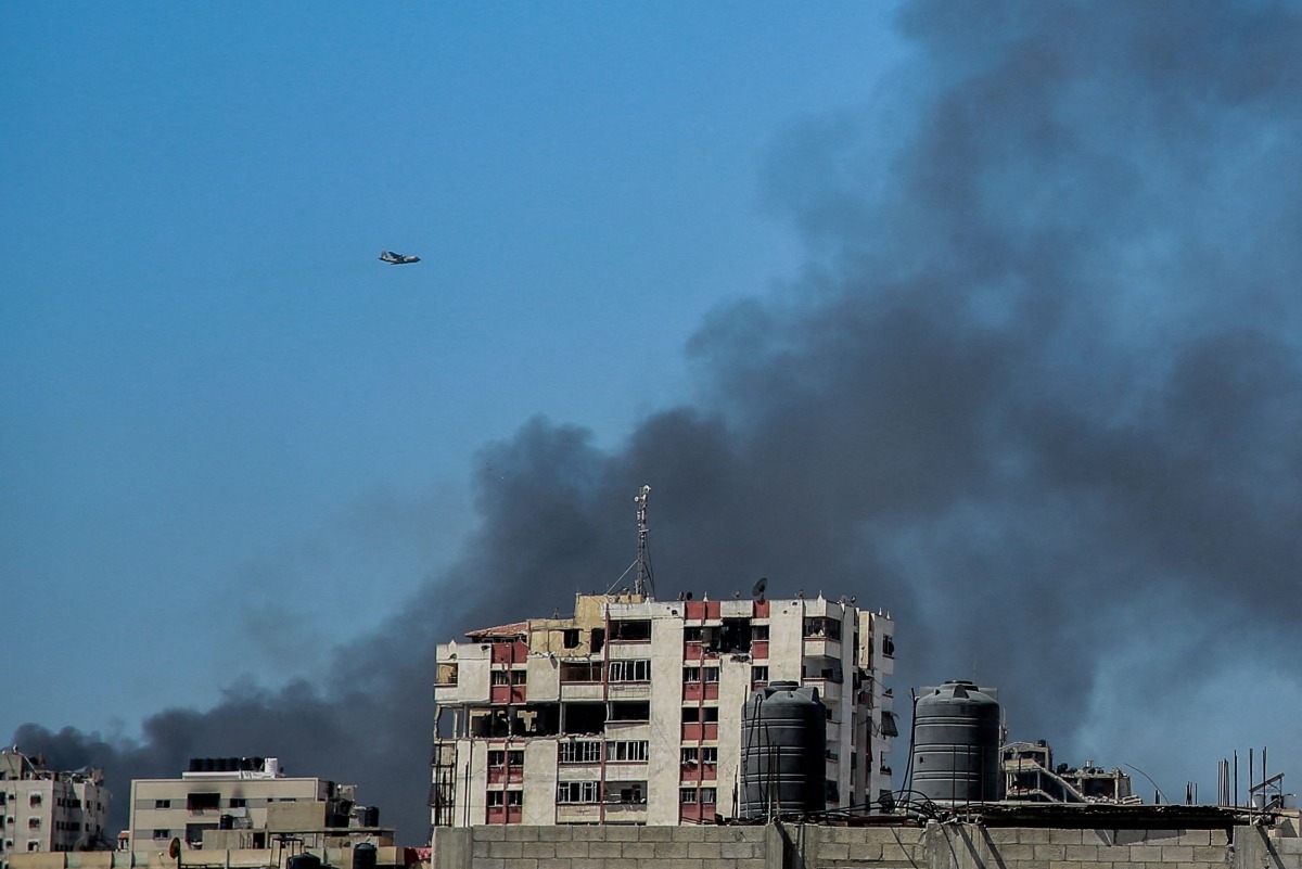 Smoke rises above the Rimal district in gaza City as a military aircraft prepares to airdrop humanitarian aid on March 20, 2024. (Photo by AFP)