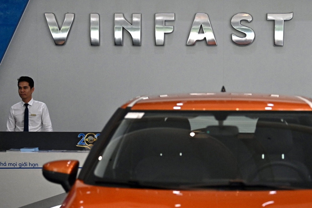 An employee stands under the VinFast logo inside a showroom for the electric vehicle maker in Hanoi on September 29, 2023. Photo by Nhac NGUYEN / AFP