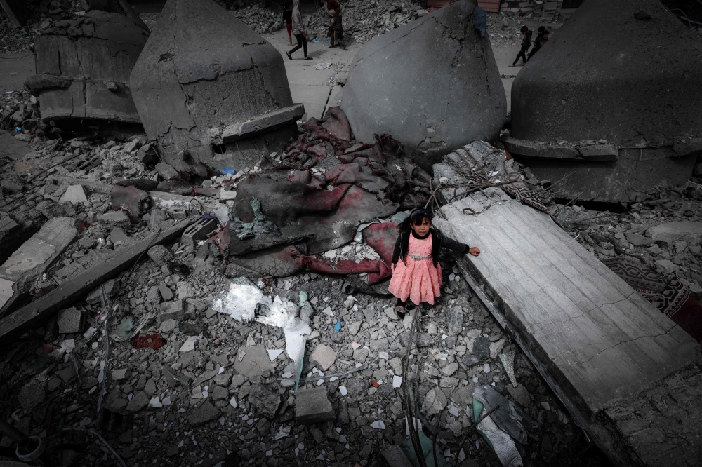 A Palestinian girl wearing a pink dress stands amidst the ruins of the Al-Faruq Mosque that was destroyed during Israeli bombardment, in Rafah on the southern Gaza Strip on March 22, 2024. (Photo by Mohammed Abed / AFP)