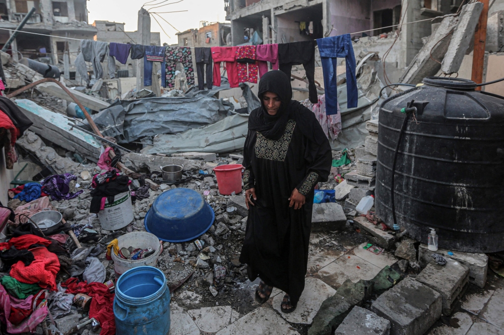 :A woman hangs laundry amidst the rubble of the Rabaya home, which was destroyed by an Israeli strike, during the Muslim holy month of Ramadan in Rafah on March 23, 2024. (Photo by SAID KHATIB / AFP)
