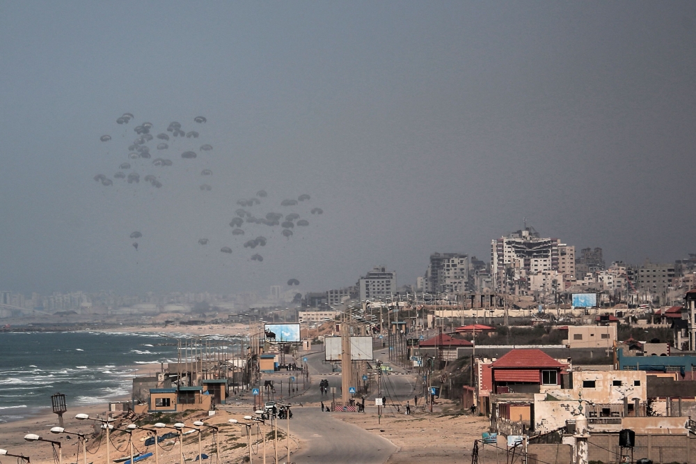 Humanitarian aid parcels attached to parachutes are airdropped from a military aircraft over the central Gaza Strip on March 21, 2024. (Photo by AFP)
