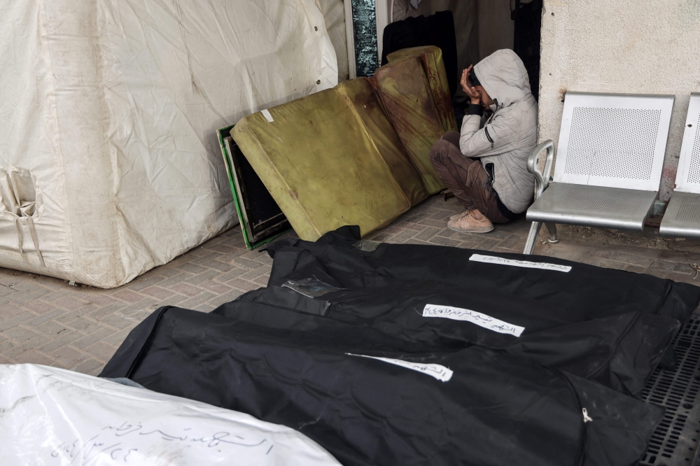 A young Palestinian boy reacts as he sits between a blood-stained mattress and body bags at the al-Najjar hospital, following overnight Israeli bombardment in Rafah in the southern Gaza Strip on March 24, 2024. (Photo by Mohammed Abed / AFP)