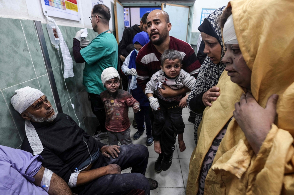 A man carries children injured in Israeli bombardment, at the al-Najjar hospital in Rafah in the southern Gaza Strip on March 24, 2024. (Photo by Mohammed Abed / AFP)