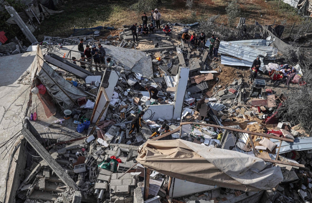 In this aerial view, Palestinians assess the destruction of a house hit by Israeli bombardment in the northern part of Rafah in the southern Gaza Strip on March 23, 2024. (Photo by SAID KHATIB / AFP)
