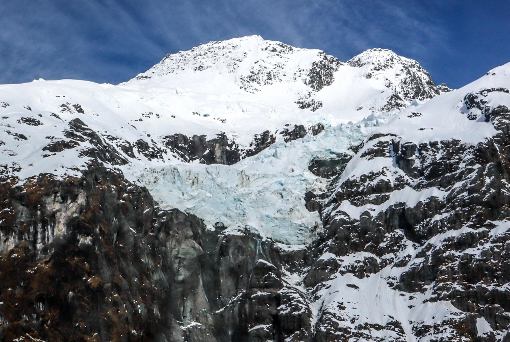 A glacier sits between mountains covered in snow in the Mount Aspiring National Park located near Queenstown on the South Island of New Zealand on October 20, 2023. Photo by David GRAY / AFP