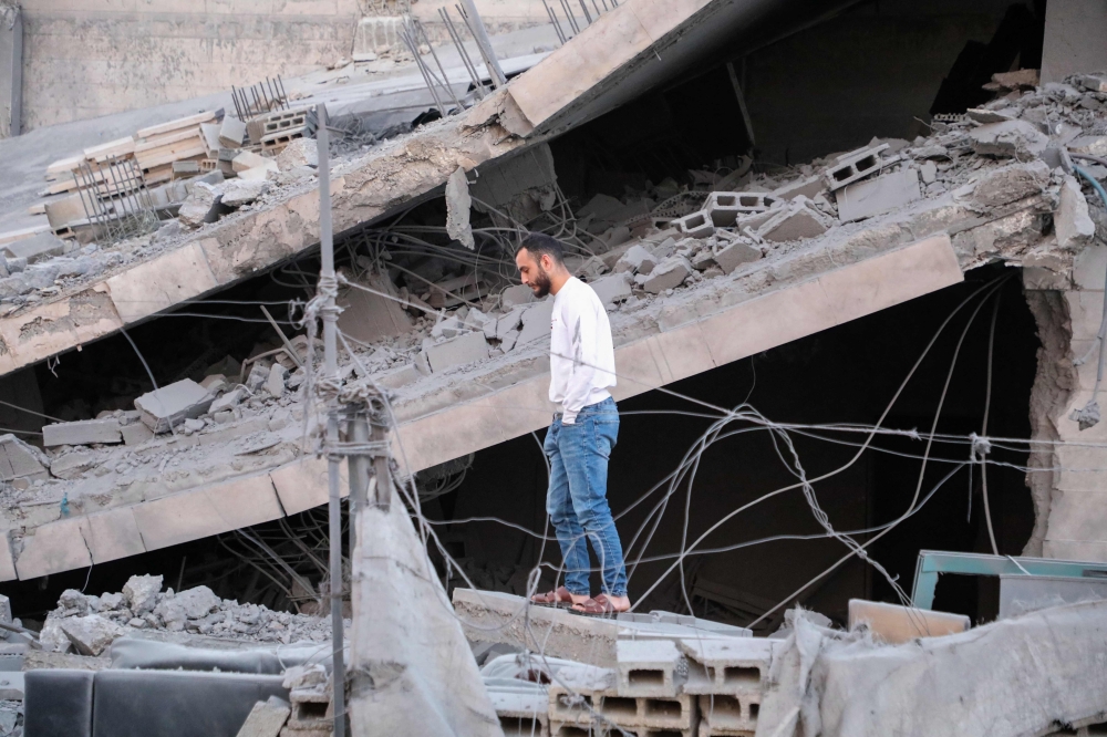 A Palestinian man stands on the rubble of a family home, demolished by Israeli forces earlier during a raid in Hebron city in the occupied West Bank on January 21, 2024. (Photo by Mosab Shawer / AFP)

