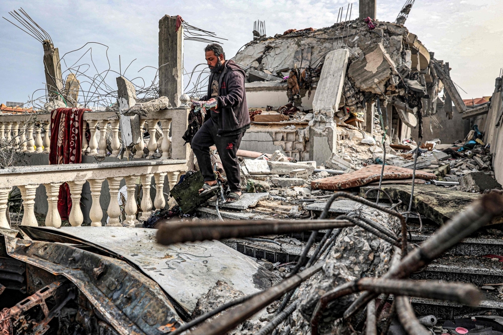 A man salvages the remains of a copy of the Holy Quran from the rubble of a building that was hit overnight during Israeli bombardment in Rafah in the southern Gaza Strip on March 26, 2024. (Photo by Said Khatib / AFP)
