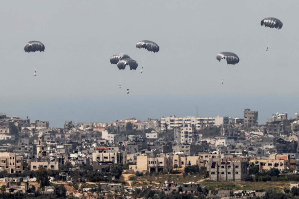 This picture taken from Israel's southern border with the Gaza Strip shows parachutes of humanitarian aid dropping over the besieged Palestinian territory on March 27, 2024. (Photo by Jack Guez / AFP)