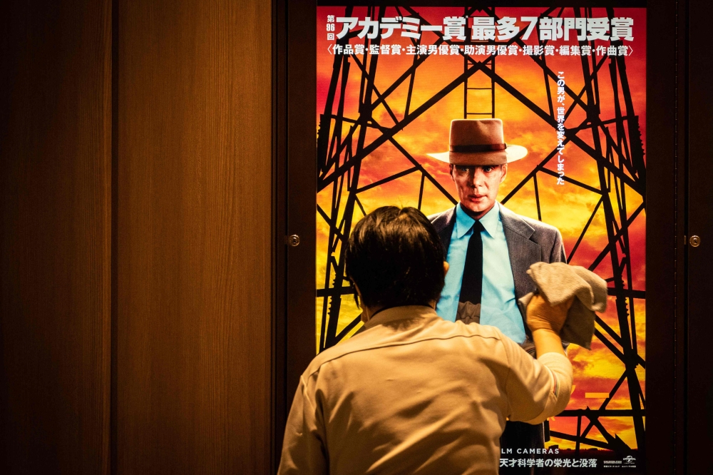 A worker cleans a screen showing an advertisement of 'Oppenheimer' in Tokyo on March 29, 2024. Photo by Yuichi YAMAZAKI / AFP