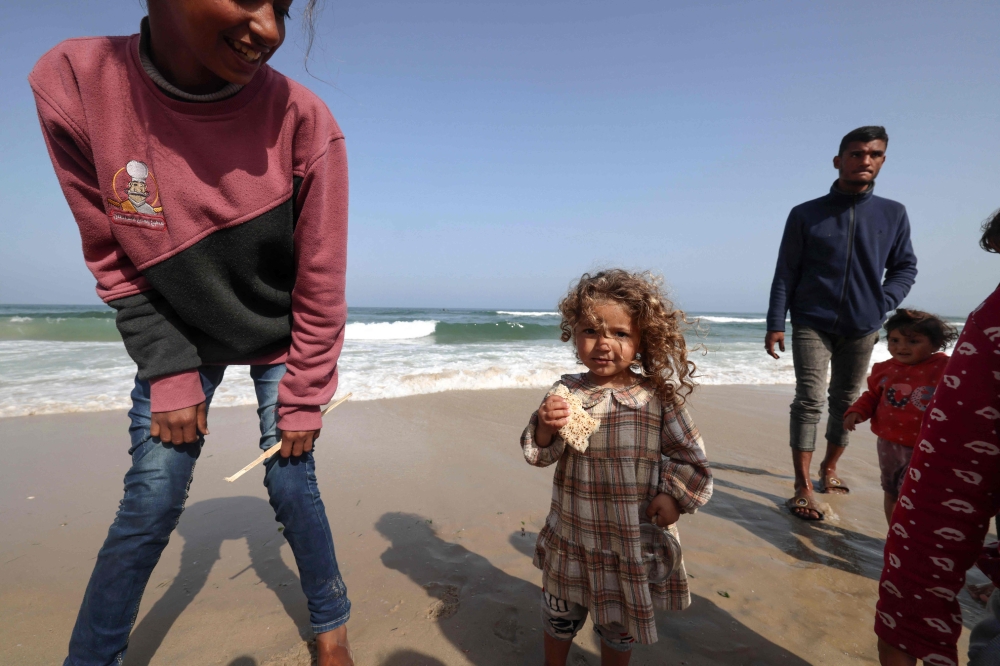 Palestinians gather along a beach adjoining a makeshift camp for displaced people in Rafah in the southern Gaza Strip on March 30, 2024. (Photo by Mohammed Abed / AFP)