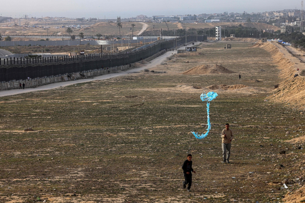 A displaced Palestinian child flies a kite near the border with Egypt in Rafah in the southern Gaza Strip on March 29, 2024. (Photo by SAID KHATIB / AFP)
