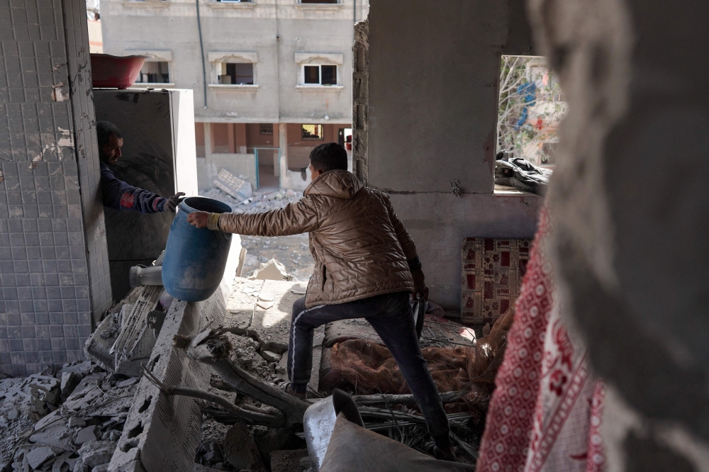 Members of the Abul Aoun family salvage some belongings from the rubble in their home destroyed during Israeli bombardment on the Al-Maghazi refugee camp in Deir Balah in the central Gaza Strip on March 31, 2024. (Photo by AFP)