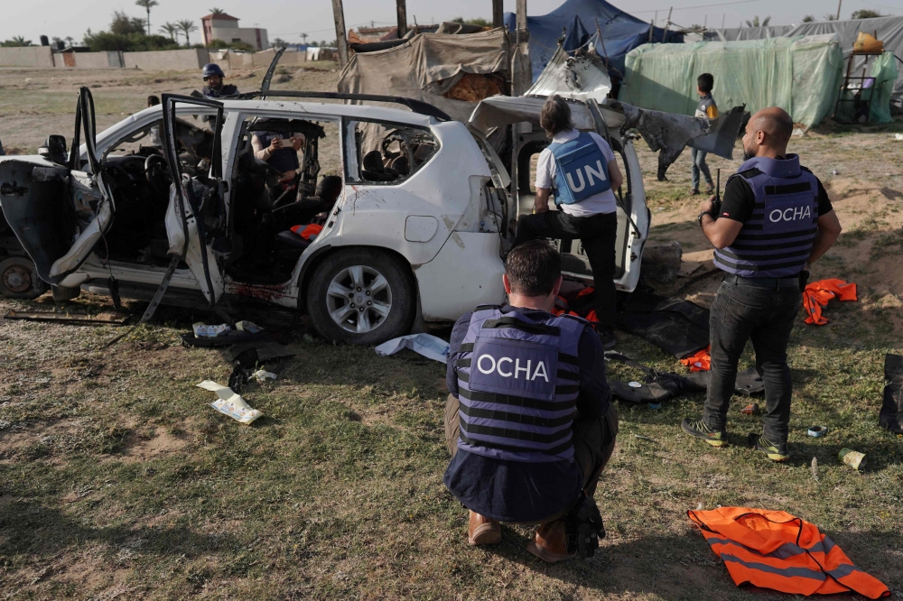 United Nations staff members inspect the carcass of a car used by US-based aid group World Central Kitchen, that was hit by an Israeli strike the previous day in Deir al-Balah in the central Gaza Strip on April 2, 2024. (Photo by AFP)