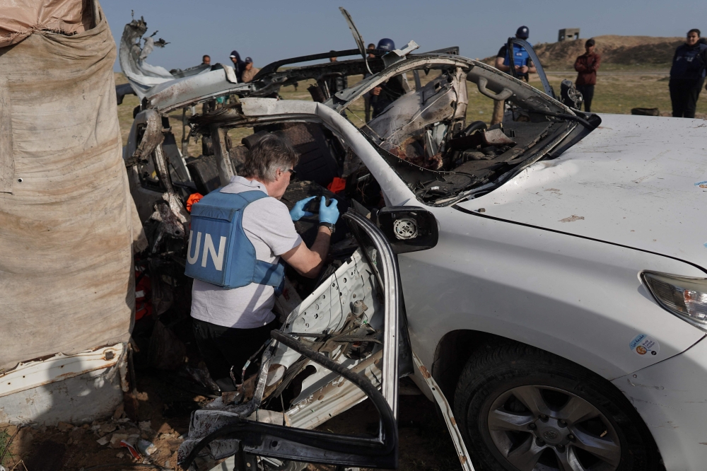 United Nations staff members inspect the carcass of a car used by US-based aid group World Central Kitchen, that was hit by an Israeli strike the previous day in Deir al-Balah in the central Gaza Strip on April 2, 2024. Photo by AFP.