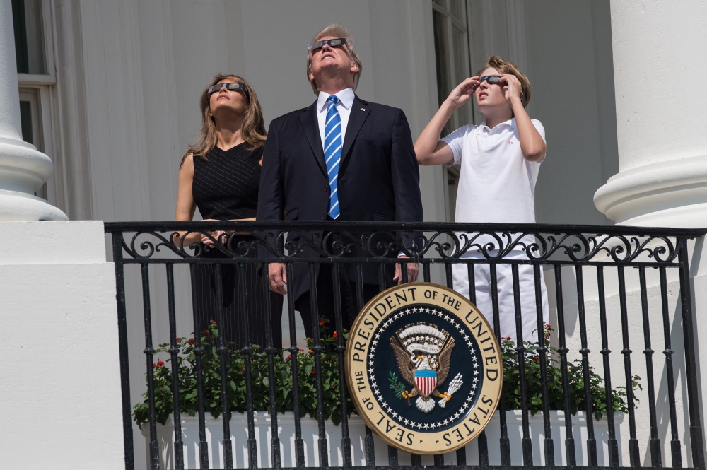 File: US President Donald Trump, First Lady Melania Trump and son Barron look up at the partial solar eclipse from the balcony of the White House in Washington, DC, on August 21, 2017. (Photo by Nicholas Kamm / AFP)