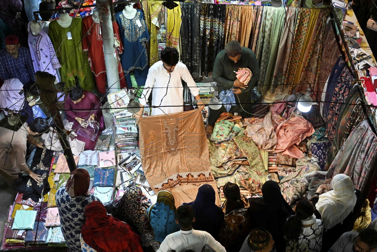 People shop clothes at a market in Karachi on April 5, 2024, ahead of Eid al-Fitr celebrations which marks the end of the Muslim holy month of Ramadan. (Photo by Asif HASSAN / AFP