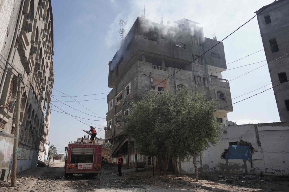 A firefighter truck deploys as smoke billows from a building following Israeli bombardment in Nuseirat, central Gaza, on April 12, 2024. (Photo by AFP)