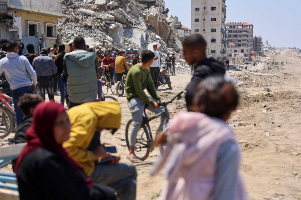 People wait on April 14, 2024, for displaced Palestinians returning to Gaza City after fleeing northern Gaza following hostilities. Photo by AFP.