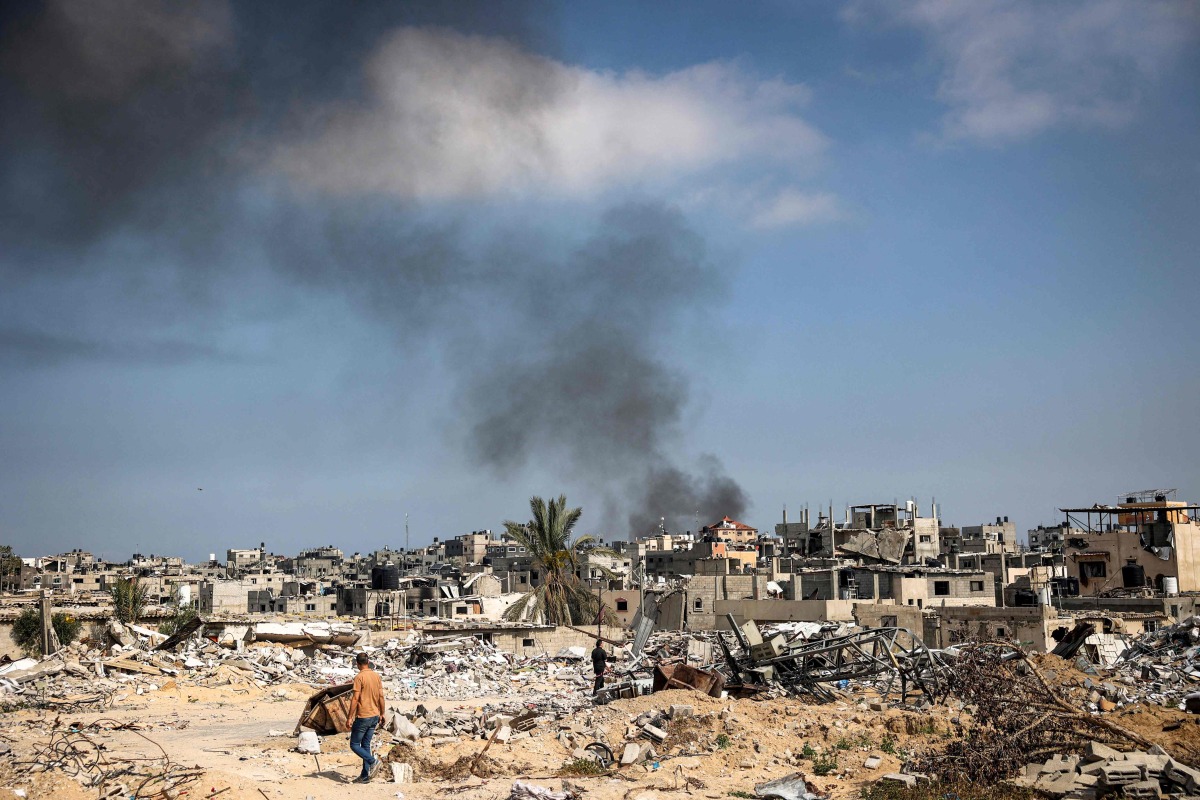 Smoke billows as a man walks amid the rubble of buildings destroyed during Israeli bombardment in Khan Yunis, on the southern Gaza Strip on April 16, 2024. (Photo by AFP)
