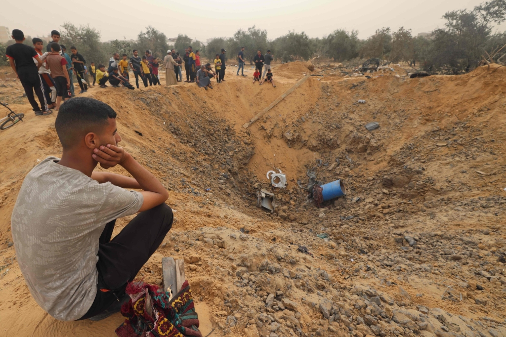 Palestinians gather around a huge crater following overnight Israeli bombardment in Rafah in the southern Gaza Strip on April 18, 2024. (Photo by Mohammed Abed / AFP)