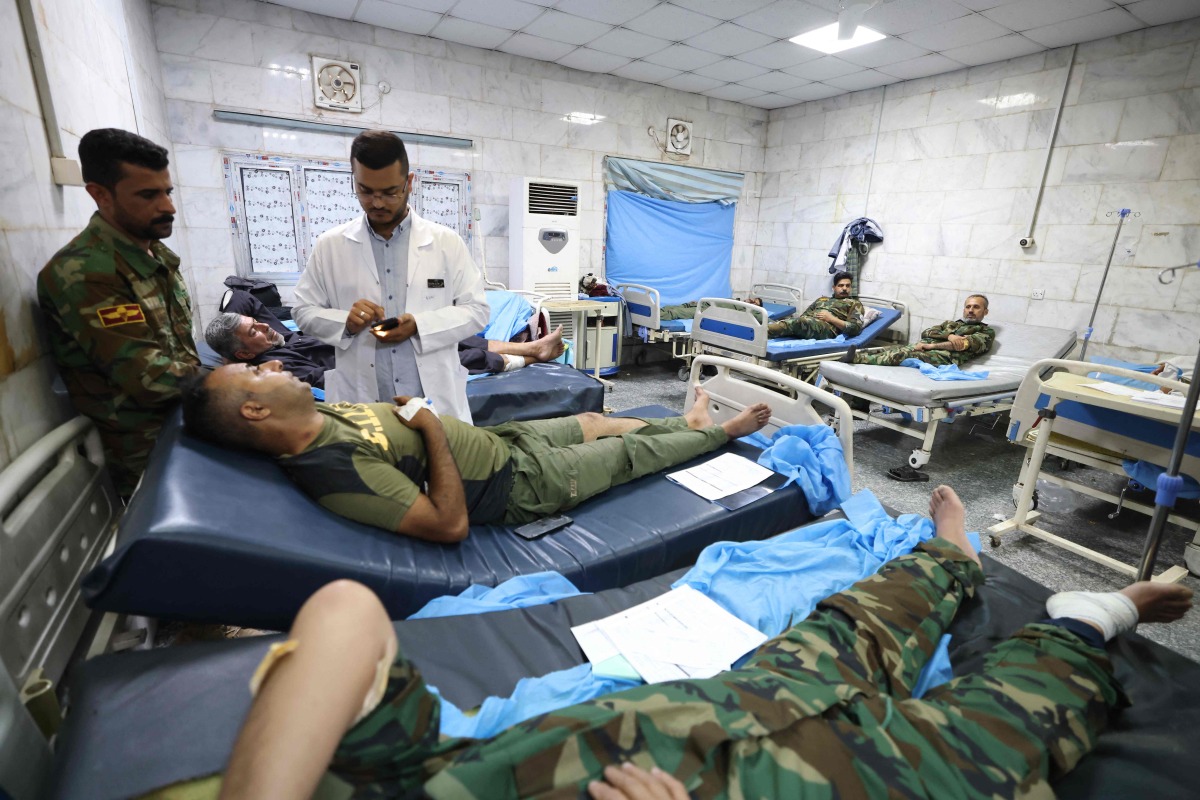 iraqi military personnel receive treatment at a hospital in Hilla in the central province of Babylon after they were wounded in an alleged bombing overnight on an iraqi military base housing a coalition of pro-Iranian armed groups, on April 20, 2024. (Photo by Karar Jabbar / AFP)
