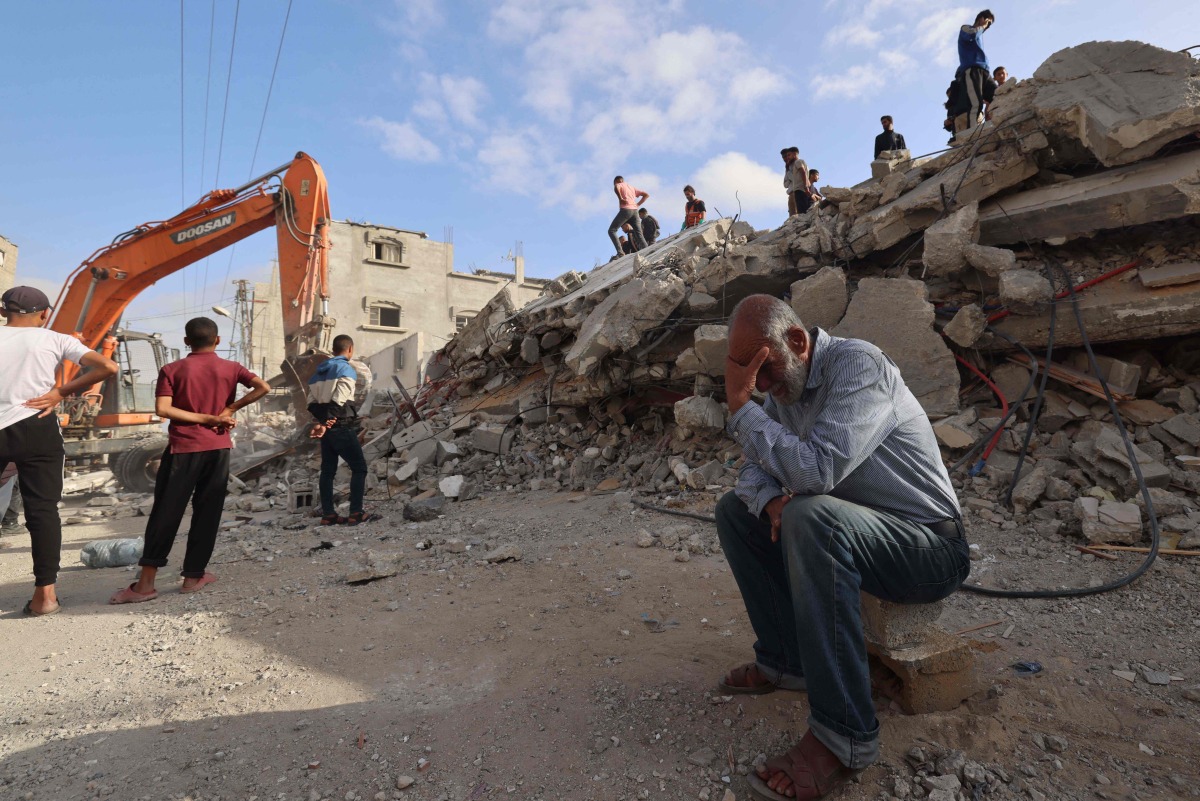 A Palestinian man wait for news of his daughter as rescue workers search for survivors under the rubble of a building hit in an overnight Israeli bombing in Rafah, in the southern Gaza Strip, on April 21. (Photo by MOHAMMED ABED / AFP)