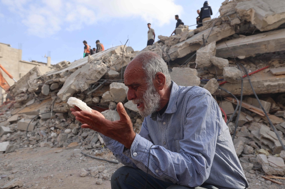 A Palestinian man wait for news of his daughter as rescue workers search for survivors under the rubble of a building hit in an overnight Israeli bombing in Rafah, in the southern Gaza Strip, on April 21, 2024. (Photo by Mohammed Abed / AFP)