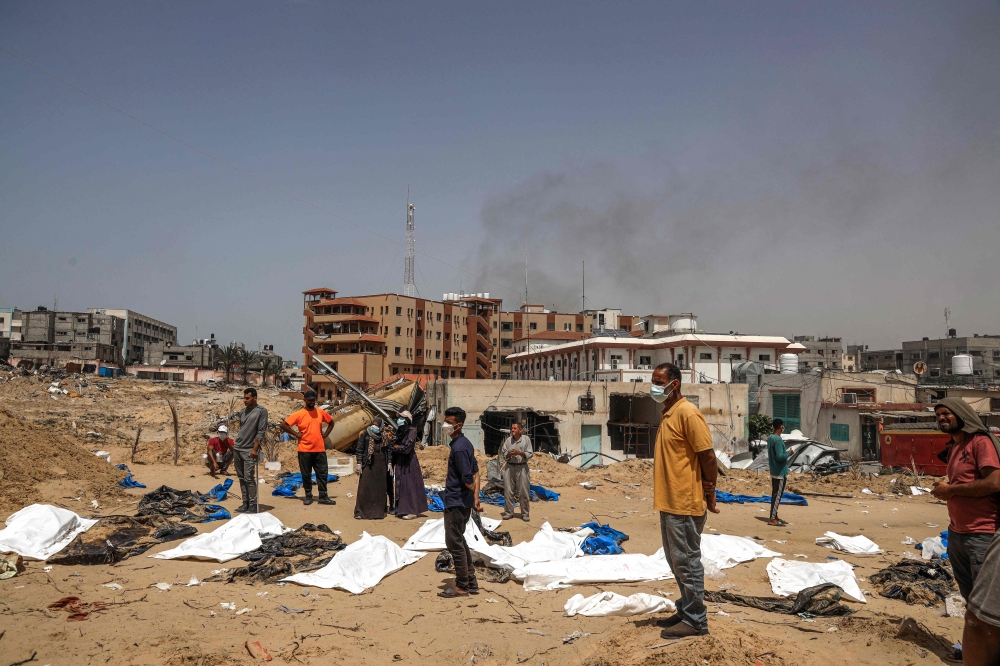 People and health workers unearth bodies found at Nasser Hospital in Khan Yunis in the southern Gaza Strip on April 23, 2024. (Photo by AFP)