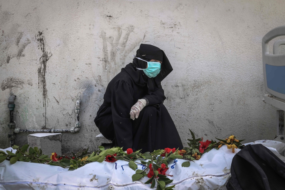 A woman mourns by a body unearthed at Nasser Hospital in Khan Yunis in the southern Gaza Strip on April 23, 2024. (Photo by AFP)
