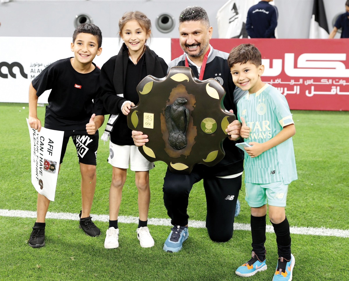 Al Sadd coach Wesam Rizik along with children poses with the Falcon Shield.