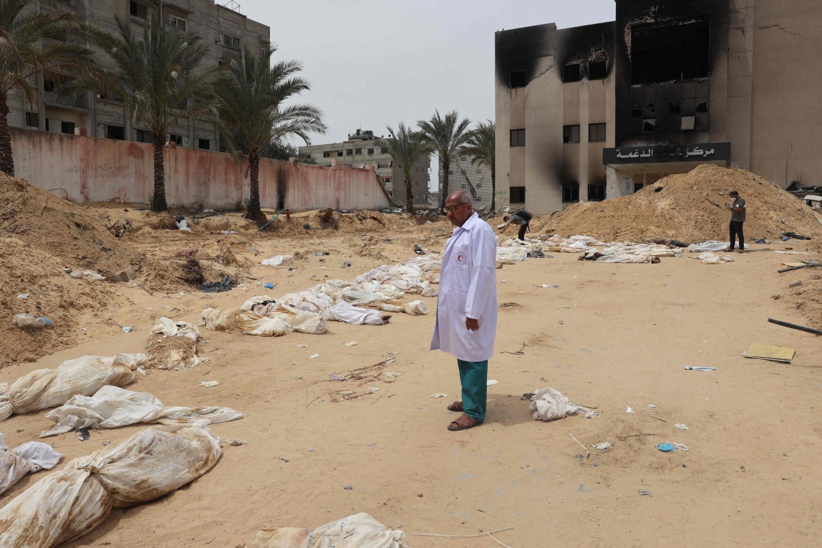 A doctor stands near bodies lined up for identification after they were unearthed from a mass grave found in the Nasser Medical Complex in the southern gaza Strip on April 25, 2024 (Photo by AFP).