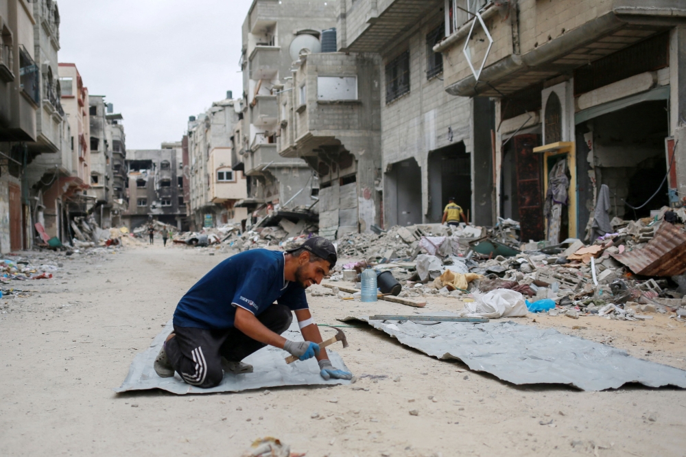 A Palestinian man fixes tin sheets used for temporary sheltering on a road lined with destroyed buildings in Khan Yunis in the southern Gaza Strip on May 2, 2024, amid the ongoing conflict between Israel and the Hamas movement. Photo by AFP.