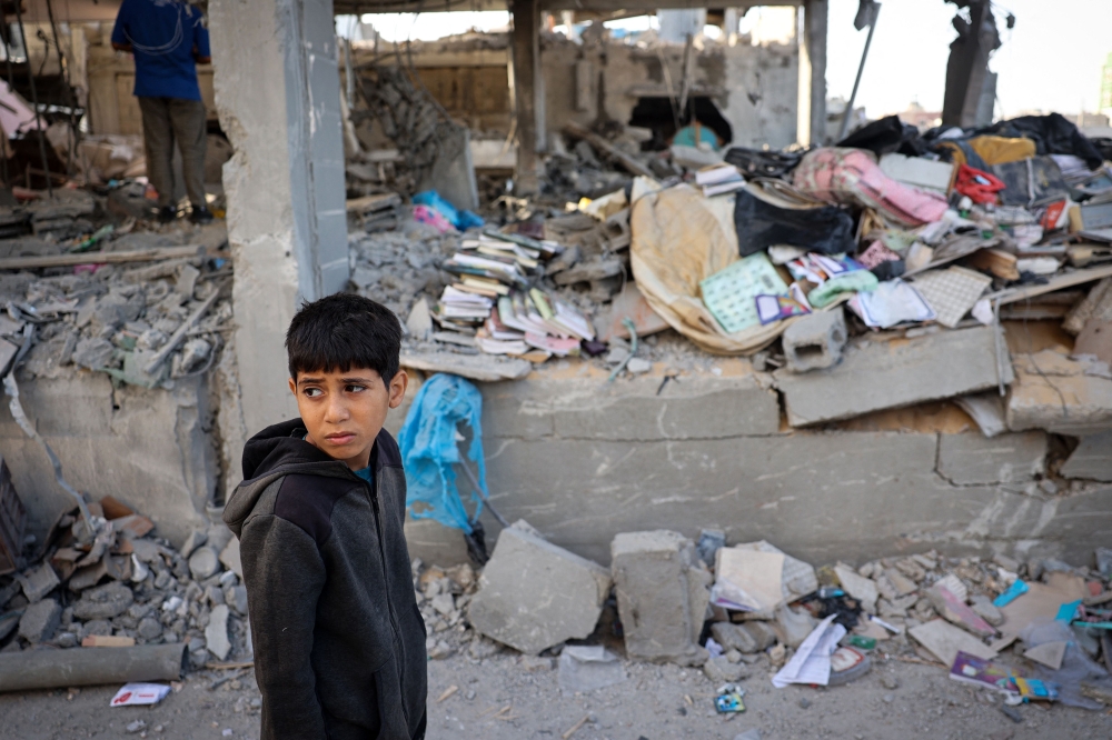 A Palestinian child stands in front of a building destroyed by Israeli bombing in Rafah in the southern Gaza Strip on May 3, 2024. (Photo by AFP)
