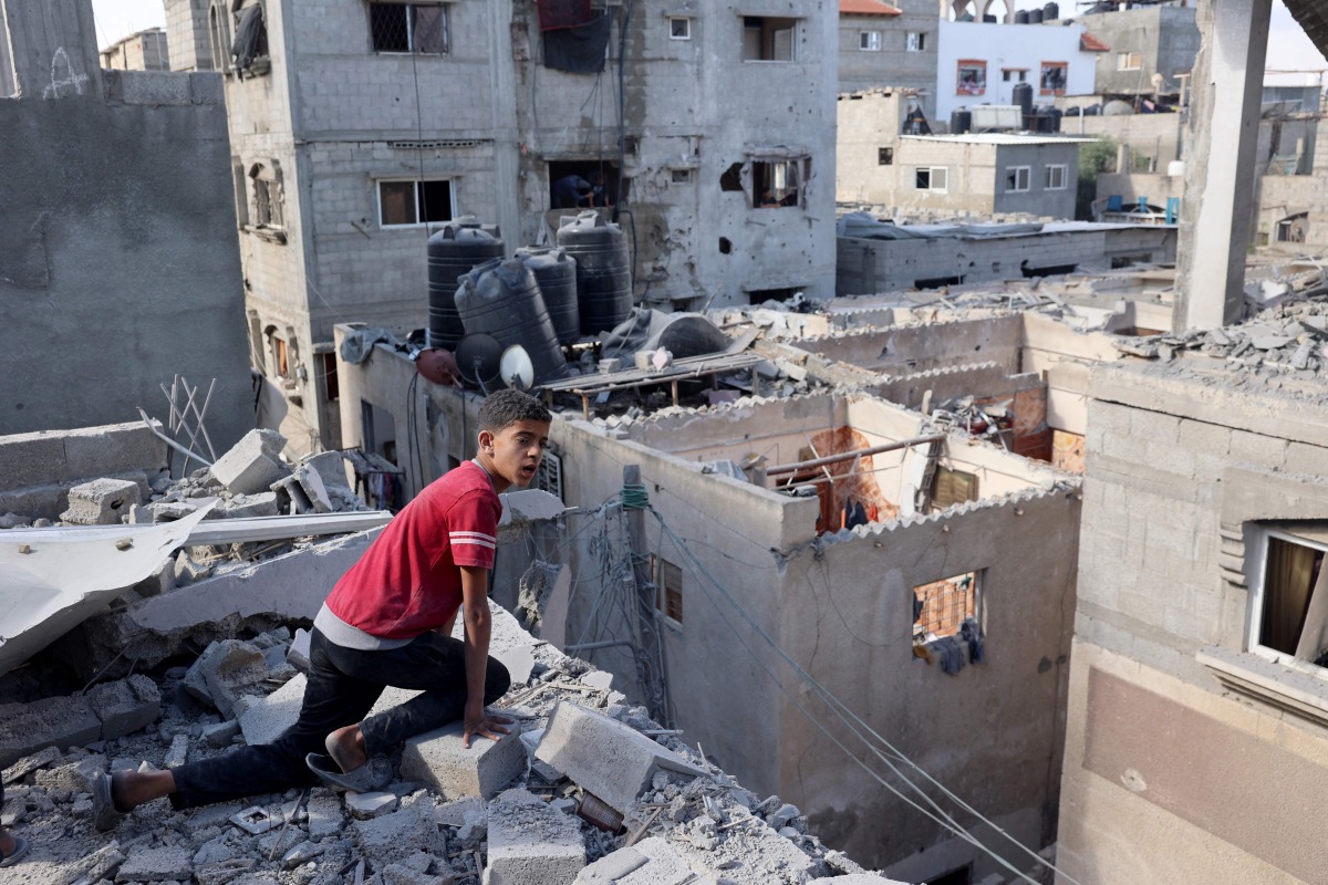 A Palestinian boy checks the destruction from the roof of a damaged house following Israeli bombardment of Rafah's Tal al-Sultan district in the southern Gaza Strip on May 7, 2024. (Photo by AFP)