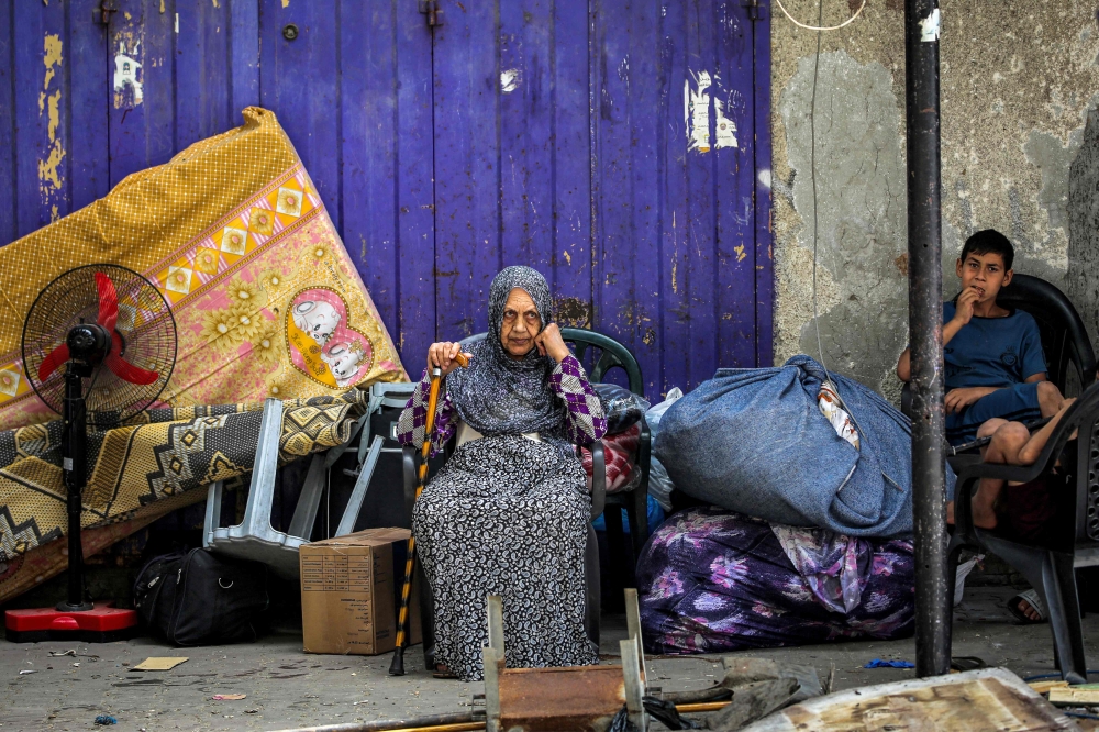 An elderly woman and child wait with belongings before evacuating from Rafah in the southern Gaza Strip on May 11, 2024. (Photo by AFP)