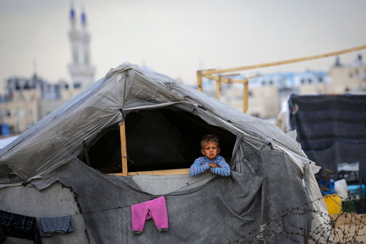 A Palestinian boy looks out his tent in a Rafah displacement camp in the southern gaza Strip on May 13, 2024 (Photo by AFP)