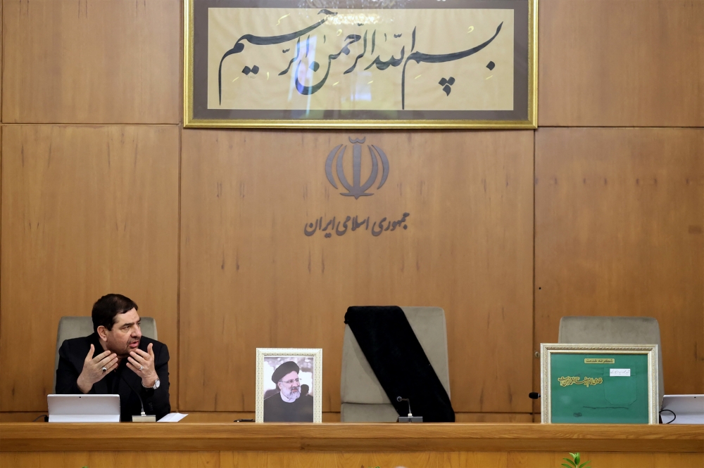 A handout picture released by the Iranian presidency shows Iran's First Vice President Mohammad Mokhber, with the seat of the late president Ebrahim Raisi (portrait) next to him empty, addressing the country's cabinet in Tehran on May 20, 2024. (Photo by Iranian Presidency / AFP) 