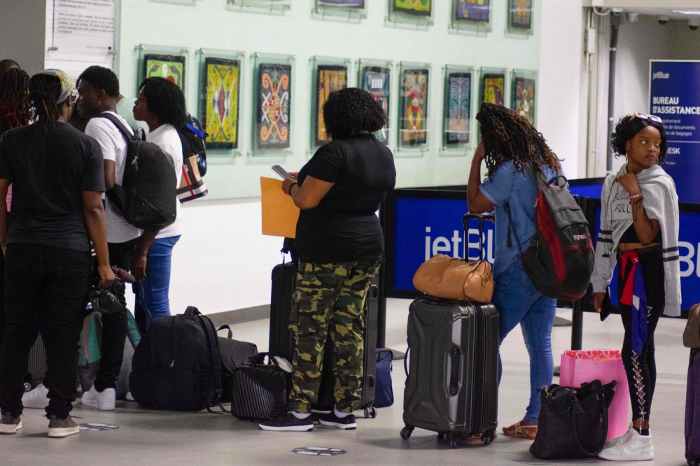 People wait in line for a flight at Toussaint Louverture Airport in Port-au-Prince on May 20, 2024. (Photo by Clarens Siffroy / AFP)

