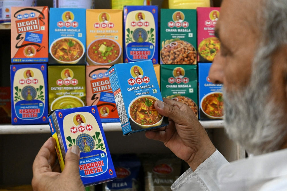 A man buys packets of MDH spices at a store in Amritsar on May 21, 2024. (Photo by Narinder NANU / AFP)