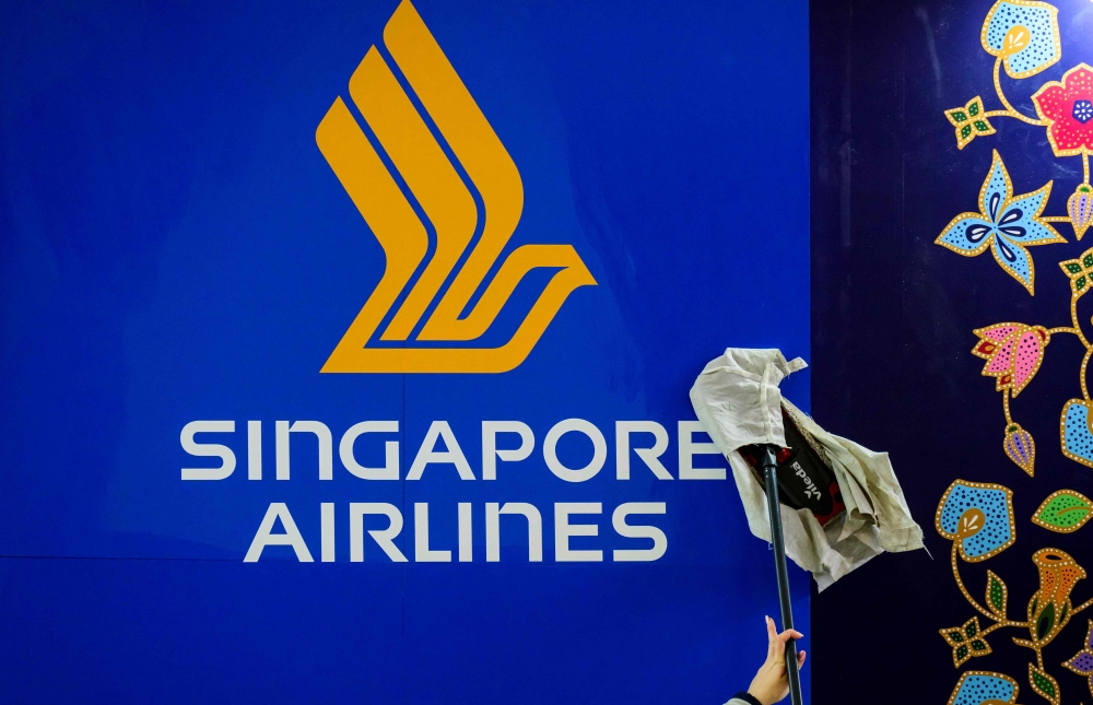 A worker wipes a Singapore Airlines logo at the International Tourism Trade Fair (ITB, Internationale Tourismusboerse) in Berlin on March 6, 2023. Photo by John MACDOUGALL / AFP